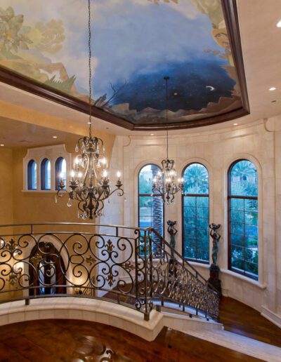 A large foyer with a chandelier and a painting on the ceiling.