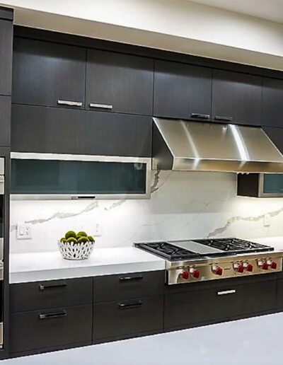 A modern kitchen with black cabinets and stainless steel appliances.