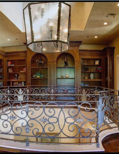 A living room with a wrought iron railing and bookshelves.