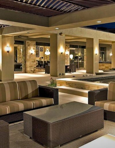 An outdoor living area with wicker furniture and a pool.