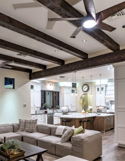 A living room with wood beams and a ceiling fan.